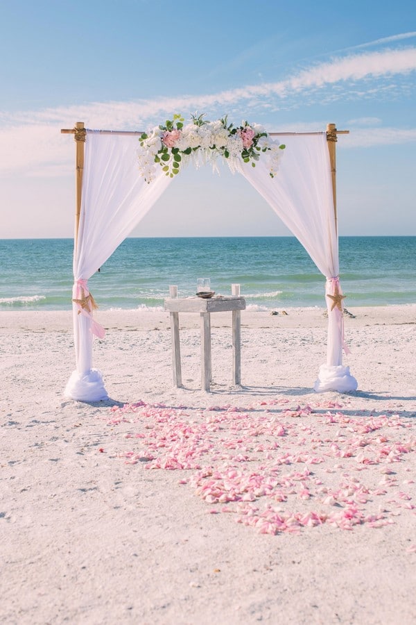White beach wedding arbor with soft pink accents