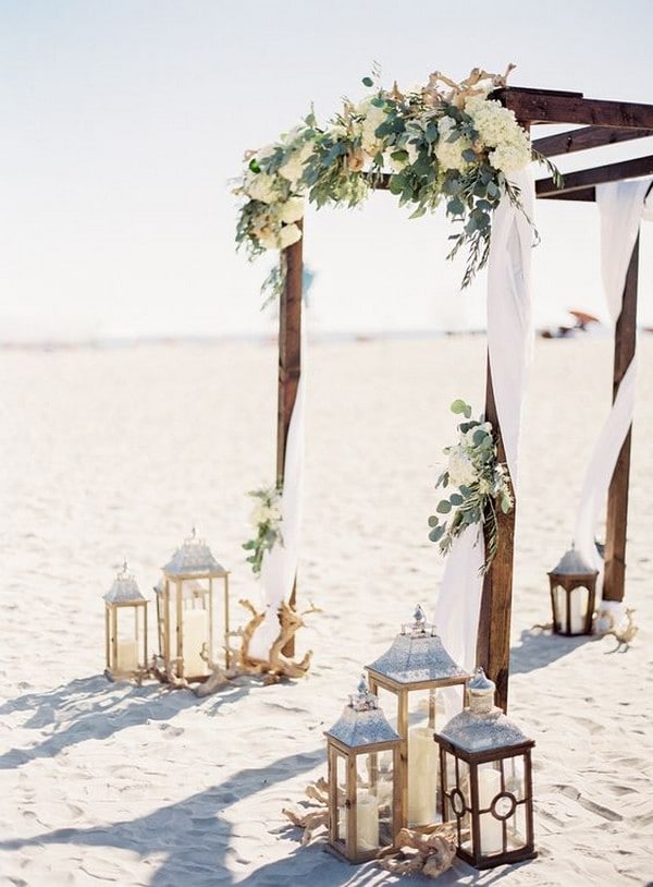 beach wedding arbor with garland and lanterns