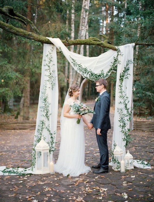 simple outdoor wedding backdrop with drapery greenery and lanterns