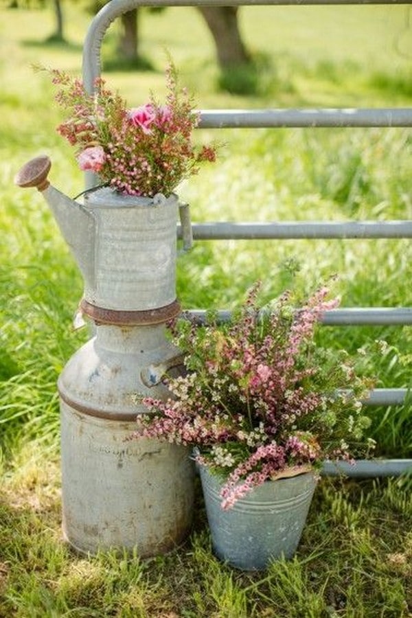 vignette of old watering cans and farm pails, adorned with flowers