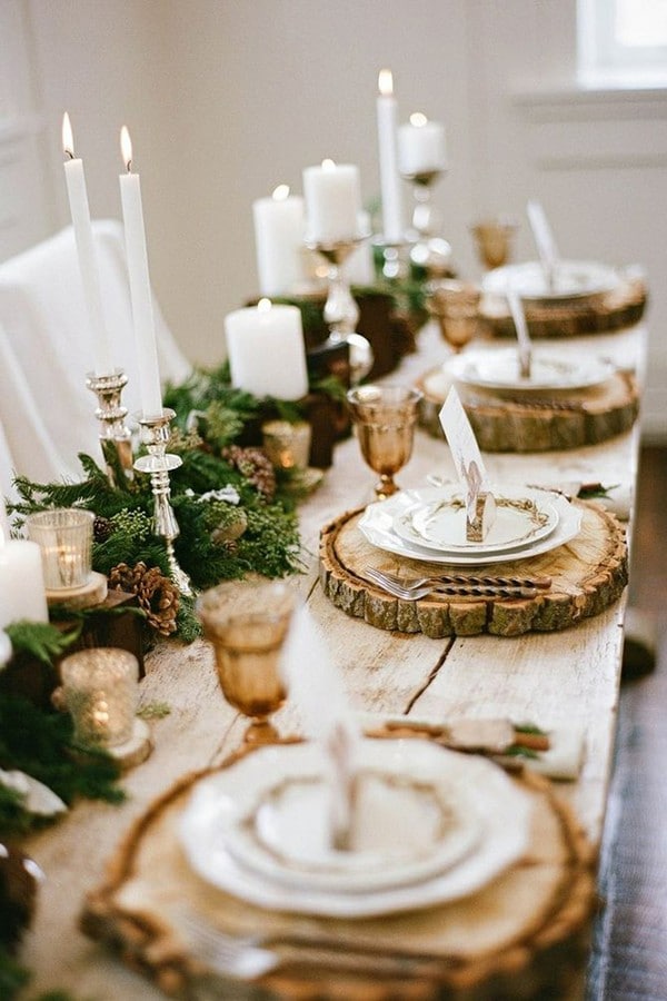 winter wedding decorations on a long wooden table decorated with fir tree branches with cones and candles plates on wooden slices jacque lynn photogaphy