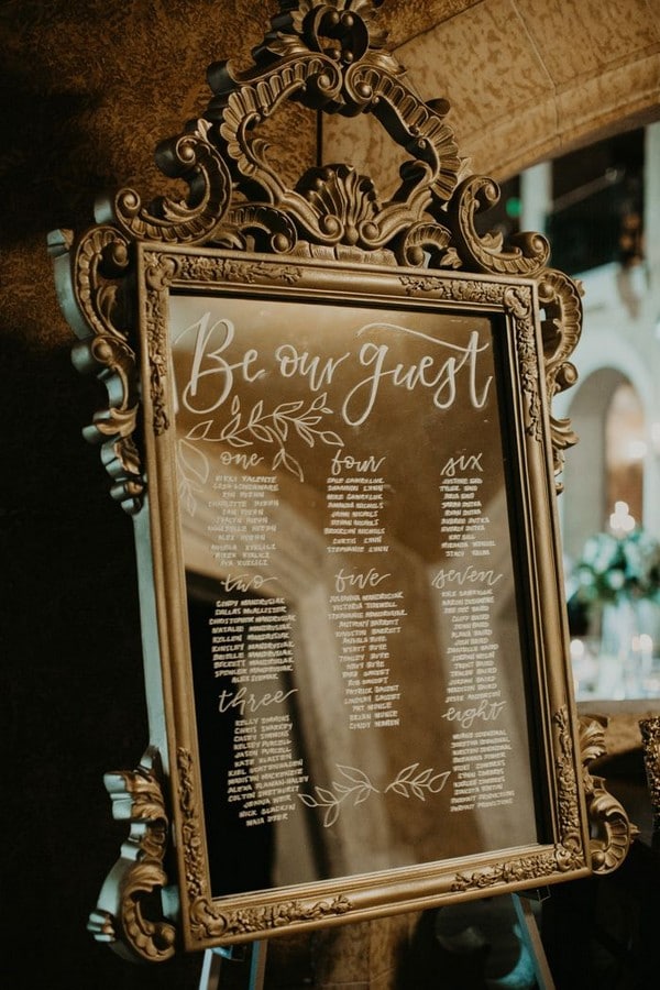 Elegant seating chart signage written on a vintage gold mirror