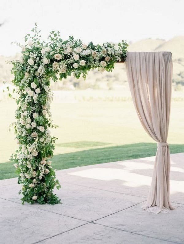 outdoor wedding floral arch with neutral drapery