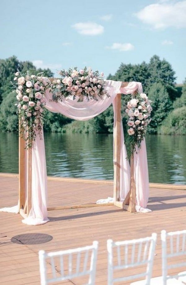 pink draped fabric and flowers wedding arch
