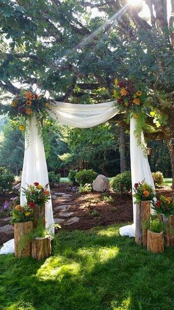 rustic fall tree stump and draped fabric wedding arch