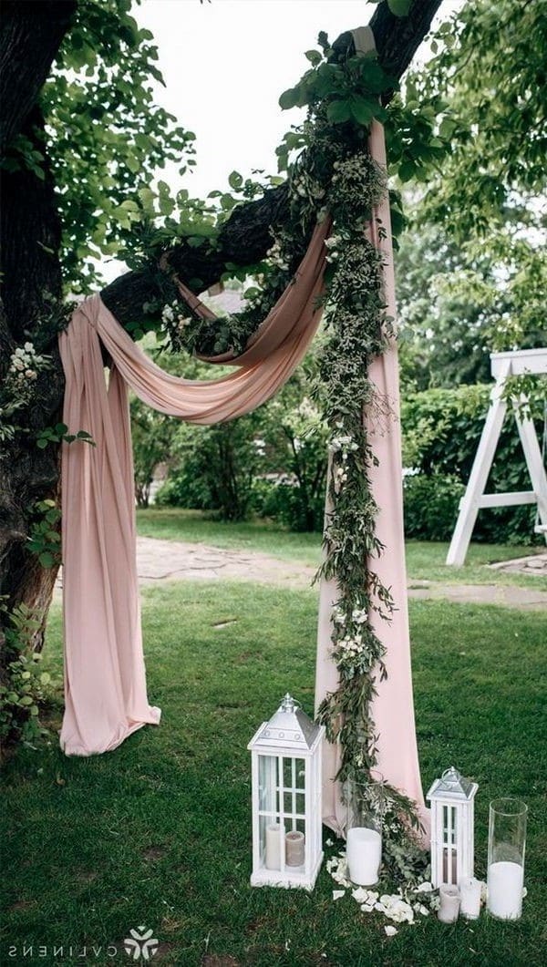 wedding ceremony arch decorated with greenery and dusty rose drapery