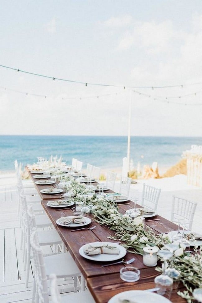 beach wedding reception decorations with long table and greenery garland